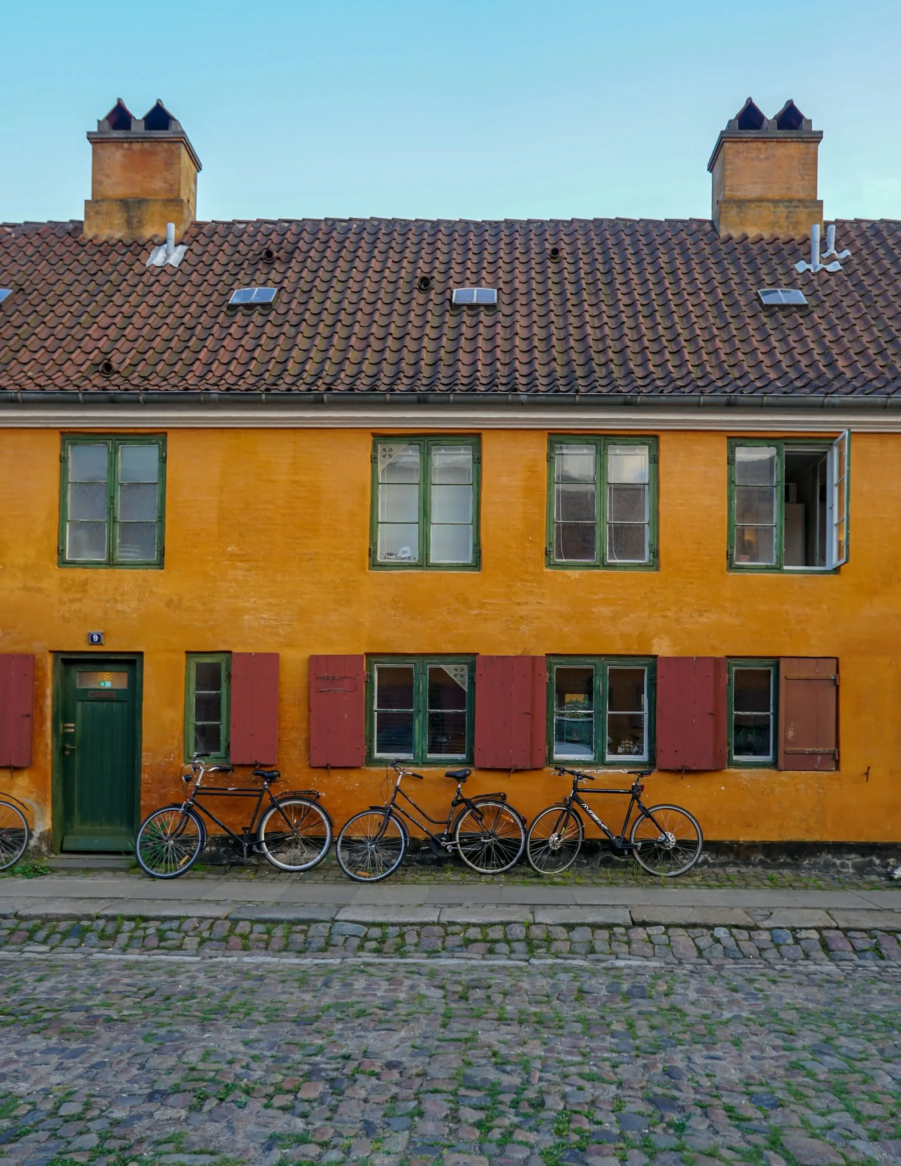 Gule rækkehuse med røde døre og cykler i København